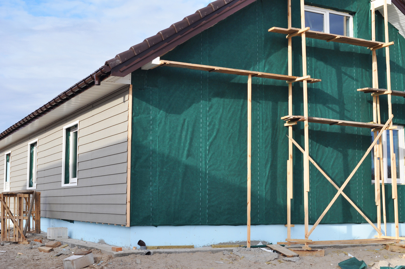 Building house with wall insulation, waterpfoof membrane, plastic siding, guttering and foundation insulation with styrofoam. Siding House, Siding installation.